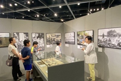 ワークショップに参加した小学生らに日本占領下のシンガポールで撮影された子どもたちの写真について説明する佐々木博子記者（右端）＝いずれも横浜市中区のニュースパーク（日本新聞博物館）で、中島みゆき撮影