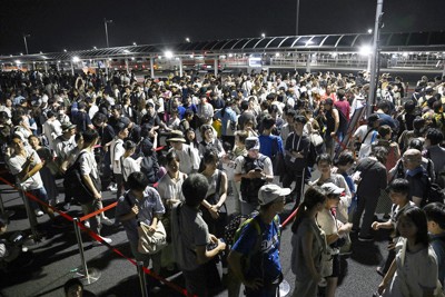 大阪メトロ中央線が運転見合わせとなり、タクシー待ちで西ゲート前に並ぶ大勢の人たち（8月13日午後11時53分撮影、共同通信）