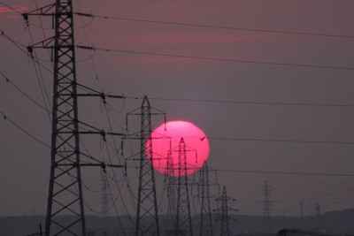 送電線の背後に写り込む太陽＝茨城県取手市で2025年8月、中村琢磨撮影