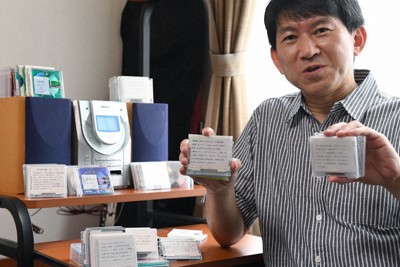 好きな音楽を集めた自作のMDを手にする栗田朋一さん。後方にあるコンポは壊れていてMDが聴けないという＝さいたま市で、宮本明登撮影