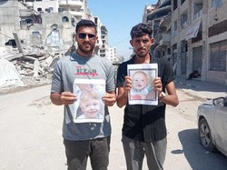 ハマスが拘束した人質の写真を掲げて路上に立つガザの住民＝パレスチナ自治区ガザ地区で2025年6月（ラミ・アマンさん提供）