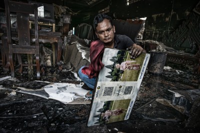 20年かけて増築した店舗兼住居をタイの砲撃で破壊されたシム・スルンさん(40)は、息子と娘が写った写真パネルを見つけ出した。「大切な場所を一瞬で失った。今は希望を持てない。私たちカンボジア人は戦争を望まない」と語り、目を伏せた＝カンボジア北部で2025年8月1日、フォトジャーナリストの高橋智史さん撮影