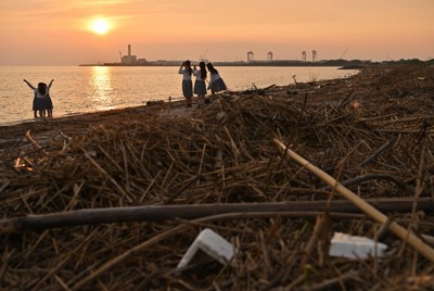 豪雨により、菊池川などから流入したとみられる大量の流木やゴミであふれかえった松原海岸。それでも、訪れた女子高生たちは夏休みの思い出作りとして、写真撮影を楽しんでいた＝熊本県玉名市で2025年8月18日、北山夏帆撮影