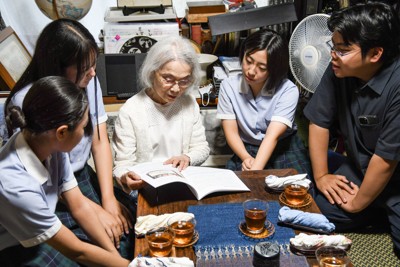 完成した冊子を眺める森滝春子さん（左から3人目）と、盈進中学高校ヒューマンライツ部の部員ら＝盈進中学高校ヒューマンライツ部提供