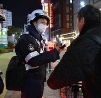 A police office conducts an alcohol breath test during a crackdown on riding under the influence of alcohol, in Fukuoka's Chuo Ward in December 2024. (Mainichi/Yuki Kurisu)