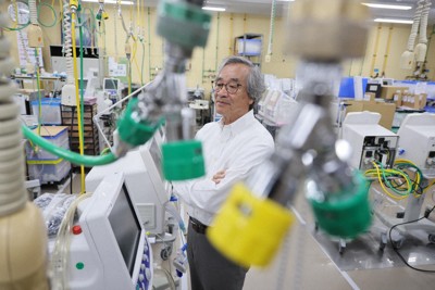 酸素チューブがさがり、製造した人工呼吸器が並ぶ社内を見つめる「メトラン」創業者の新田一福さん＝埼玉県川口市で2025年9月12日、和田大典撮影