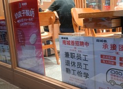 赤い字で「招聘（募集）中」と記した求人張り紙を掲示する北京市内の飲食チェーン店。定年退職者や学生バイト、副業を探す人を求めていた＝2025年9月7日、河津啓介撮影