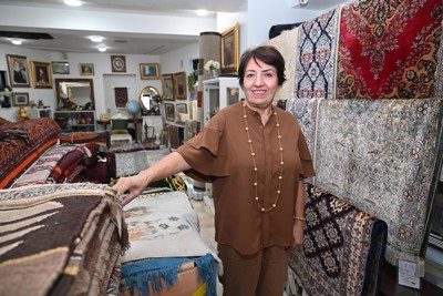 アフガニスタンのじゅうたんなどが並ぶ「ハリーロード」店舗と江藤セデカさん　撮影＝武市公孝