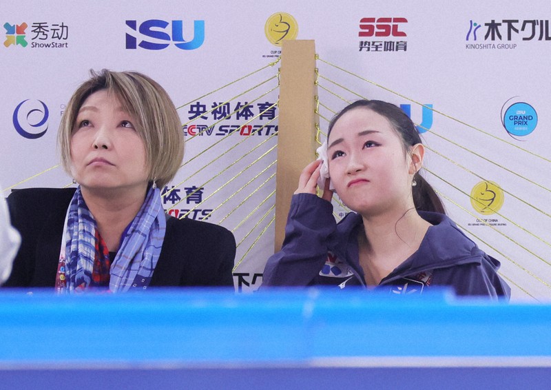 女子SPで演技を終え、汗を拭いながら得点を見つめる松生理乃（右）＝中国・重慶で2025年10月24日、吉田航太撮影