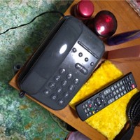 母が注文の際に使う電話。緑色のラグ、化粧品、黄色いふきん、ヘアブラシはいずれもテレビショッピングで購入したものだ＝佐藤学さん（仮名）提供