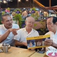 マレーシア・ペナンの懇親会場で、被爆者の肖像画を収めた画集を紹介する増田正昭さん（中央）＝増田さん提供