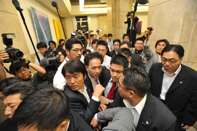 大阪府議会は議員定数削減条例案をめぐり大紛糾。浅田均議長（当時、中央）を護衛しながら議場に入る議員ら＝大阪市中央区で2011年6月3日午後11時47分、宮間俊樹撮影