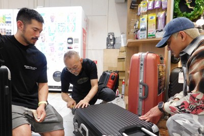 スーツケース修理の依頼に応じる中村一登さん（中央）＝千葉県成田市の成田空港で2025年10月7日午後4時半ごろ、合田月美撮影