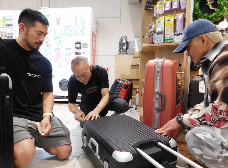 スーツケース修理の依頼に応じる中村一登さん（中央）＝千葉県成田市の成田空港で2025年10月7日午後4時半ごろ、合田月美撮影
