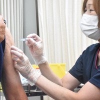 新型コロナウイルスワクチンの定期接種を受ける男性（左）＝東京都板橋区で2024年10月1日午前9時7分、肥沼直寛撮影