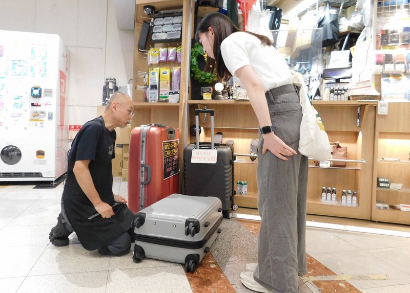 旅行者たちのスーツケース修理の依頼に応じる中村一登さん（左）＝千葉県成田市の成田空港で2025年10月7日午後4時30分、合田月美撮影