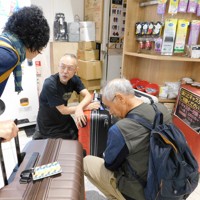 旅行者たちのスーツケース修理の依頼に応じる中村一登さん（中央）＝千葉県成田市の成田空港で2025年10月7日午後4時30分、合田月美撮影