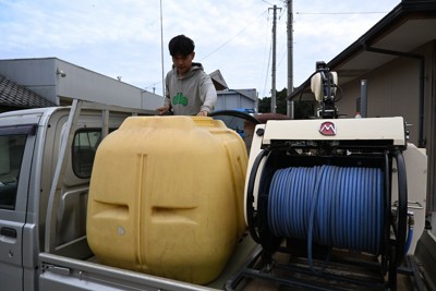 軽トラックの荷台で消毒の準備作業を進める、特定技能のインドネシア人＝茨城県鉾田市で2025年10月10日午後3時41分、千脇康平撮影