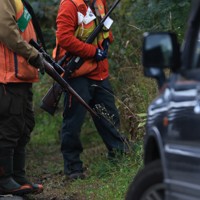 円山西町の住宅街で、ヒグマが住宅の庭に居座ったため出動したハンターら。ハンターは猟銃、警察官はクマ撃退スプレーを手にしていた＝札幌市中央区で2025年10月16日、宮間俊樹撮影