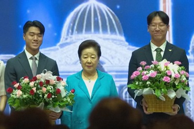 旧統一教会の集会に現れた韓鶴子総裁（中央）。後継者とされる孫の文信出氏（左）と文信興氏＝教団系のユーチューブチャンネル「HJ　Peace　TV」の7月26日付の映像より