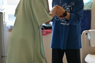 転倒しないように長男を支える女性（右）。通所施設に通っていた頃は歩けていたが、今は難しくなってしまった＝栃木県下野市の自治医科大付属病院で2025年8月21日午後1時12分、御園生枝里撮影