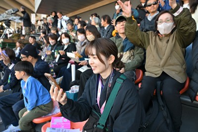 QRコードをスマートフォンで読み取り、テキスト化された実況を見ながら観戦する大垣京佳記者（手前）＝駒沢オリンピック公園総合運動場で2025年11月24日、西夏生撮影