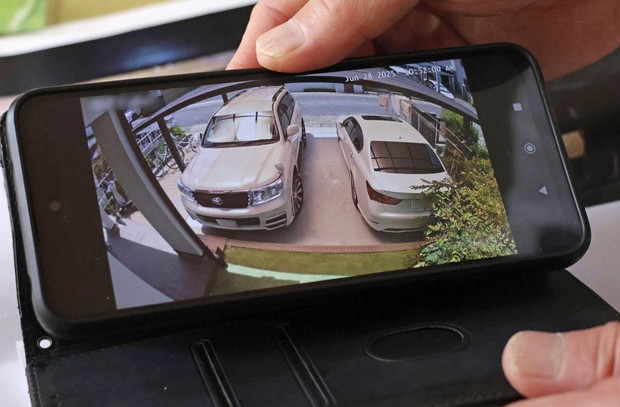 A smartphone linked to security cameras shows a man's parking lot in Nagoya, central Japan on June 28, 2025. (Kyodo)