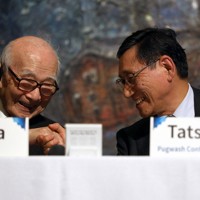 パグウォッシュ会議世界大会の全体会議に出席した鈴木達治郎さん（右）。日本被団協の田中熙巳さんと笑顔で握手した＝広島市中区の広島国際会議場で2025年11月1日、佐藤賢二郎撮影