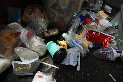 自販機の回収容器の周りに散乱するゴミ。事業者が屋外にゴミ箱を置くと無関係なゴミまで集中的に捨てられてしまうのが実情だ＝東京都渋谷区で2025年12月6日午前5時半、尾崎修二撮影