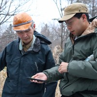 林の中でヒグマの痕跡を確認する「ガバメントハンター」の浦田剛さん（左）と新人の小田中温さん＝北海道占冠村で2025年11月26日午後3時34分、後藤佳怜撮影