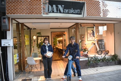 レンタル用の電動バイクや風呂おけを紹介する(右から)栗田豊一さんと典代さん＝東近江市八日市本町の「ほんまちホテル」で、伊藤信司撮影