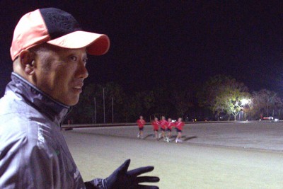 選手らが走るグラウンドを見つめる宇和高校の和家哲也監督＝愛媛県西予市で、目野創撮影