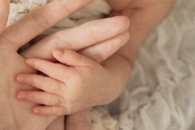 今年6月に生まれた娘に手を添える佐々木さん夫婦＝佐々木楓さん提供