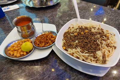 カイロの有名店アブ・ターレクのコシャリ。別皿のひよこ豆とフライドオニオンを乗せてからトマトソースをかける＝カイロで2023年5月2日午後5時31分、金子淳撮影