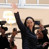 オスロにあるホテルのバルコニーから姿を現し、手を振るノーベル平和賞受賞者のマチャド氏＝ノルウェーで2025年12月11日、ロイター