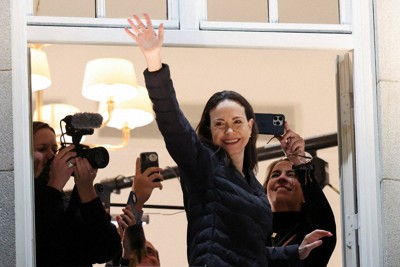 オスロにあるホテルのバルコニーから姿を現し、手を振るノーベル平和賞受賞者のマチャド氏＝ノルウェーで2025年12月11日、ロイター