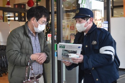買い物客にチラシを配って情報提供を呼びかける警察官（右）＝松山市で2025年12月10日午前11時9分、広瀬晃子撮影