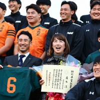 東福岡高校ラグビー部だった広木淳さんに授与された特別卒業証書を手に、記念写真に納まる母ますみさん（前列中央右）と当時の主将で早稲田佐賀高ラグビー部監督の山下昂大さん（同左）＝福岡市博多区で2025年12月11日、玉城達郎撮影