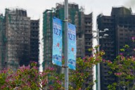 高層住宅群の火災現場近くに掲げられた立法会選挙の投票日を知らせるバナー＝香港北部・新界地区の大埔で12月3日、AP