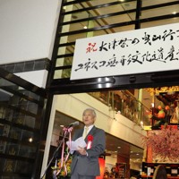 滋賀県書道協会理事長・毎日書道会評議員の神田浩山さんが筆を執ったユネスコ登録を祝う看板下であいさつする佐藤健司大津市長＝大津市中央1の大津祭曳山展示館で2025年12月11日午後6時14分、岸桂子撮影