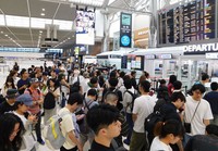 This photo taken Aug. 8, 2025, shows air passengers forming a line before they undergo security checks at Narita Airport in Chiba Prefecture. (Mainichi/Tsukimi Goda)