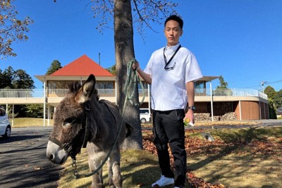 ロバを散歩させながら、周囲を案内する福祉楽団理事長の飯田大輔さん＝千葉県香取市の恋する豚研究所で