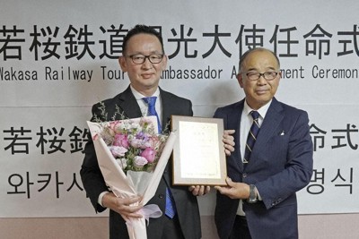 若桜鉄道の矢部雅彦専務（右）から観光大使の任命状を受け取った尹熙一さん＝韓国・大田で、共同
