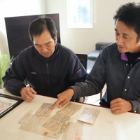 新さんが出征中に家族に宛てた手紙を見る（左から）長男粲さんと孫の新五さん親子。卓上にあるのは新さんの遺影＝福岡県筑後市馬間田で2025年12月15日午後2時20分、谷由美子撮影