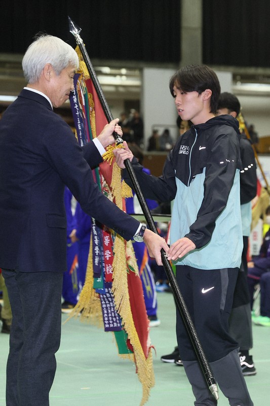 第76回男子全国高校駅伝で優勝し、優勝旗を受け取る学法石川の選手＝京都市右京区の京都市体育館で2025年12月21日、長澤凜太郎撮影