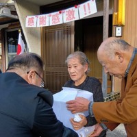 DNA鑑定で父細川利男さんと判明した遺骨を徳島県職員（左）から受け取る青山誠子さん（中央）＝徳島県美馬市で2025年12月23日午後4時2分、植松晃一撮影