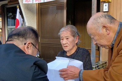 DNA鑑定で父細川利男さんと判明した遺骨を徳島県職員（左）から受け取る青山誠子さん（中央）＝徳島県美馬市で2025年12月23日午後4時2分、植松晃一撮影