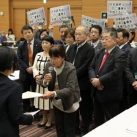 政府の担当者（左）に要請書を手渡す「長生炭鉱の水非常を歴史に刻む会」の井上洋子代表理事（中央）＝衆院第1議員会館で2025年12月23日午後1時21分、後藤由耶撮影