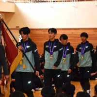 全国高校駅伝で優勝し、優勝旗を先頭に報告会場に入場するメンバー＝福島県石川町の学法石川高で2025年12月23日、西川拓撮影