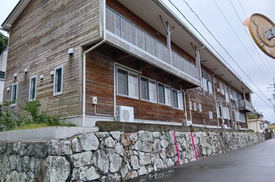 松鶴城跡の石垣の上に建つ椿泊小の校舎。写真に書き込んだ赤い実線に挟まれた付近に、絵図にも描かれた海から館へ出入りする門があったとされる＝徳島県阿南市椿泊町の市立椿泊小で2025年10月26日午後0時1分、植松晃一撮影